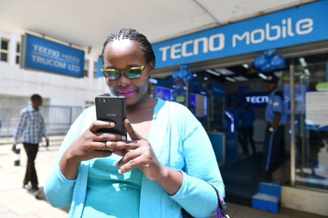 A woman uses her Tecno smartphone outside a Tecno retail store in Kenya’s Nairobi, May 9, 2017. Tecno is one of the three major phone brands of Transsion. [Photo: Xinhua]