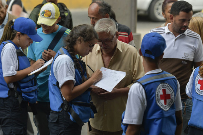 People queue to receive drums to collect water and water purification tablets from members of the Venezuelan Red Cross in Caricuao neighborhood in Caracas, Venezuela, on April 16, 2019. [Photo: AFP/Matias Delacroix]