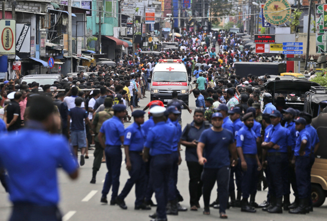 Sri Lankan police officers clear the road as an ambulance drives through carrying injured of Church blasts in Colombo, Sri Lanka, on April 21, 2019. [Photo: AP/Eranga Jayawardena]