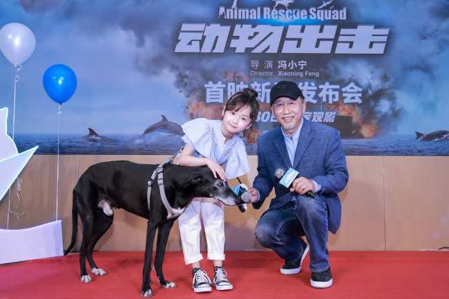 Director Feng Xiaoning (right) and his main cast including a little girl and a dog pose at a promotional event held on April 23, 2019 for their upcoming film Animal Rescue Squad. [Photo provided to China Plus]