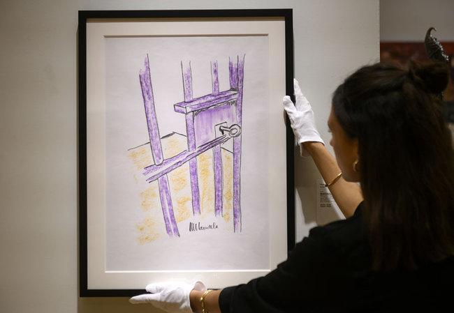 A worker holds a sketch by Nelson Mandela -- "The Cell Door, Robben Island" -- on April 26, 2019 in New York City. [Photo: AFP/JOHANNES EISELE]