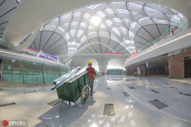 A worker is seen inside the terminal(航站楼) building of the new Beijing Daxing International Airport on April 26, 2019. The new facility south of the capital is set to begin operation(运行 yùnxíng) at the end of September. [Photo: IC]