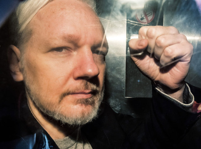 WikiLeaks founder Julian Assange gestures from the window of a prison van as he is driven into Southwark Crown Court in London on May 1, 2019, before being sentenced to 50 weeks in prison for breaching his bail conditions in 2012. [Photo: AFP]