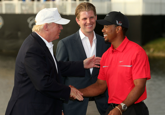 FILE - In this file photo taken on March 09, 2013 Developer Donald Trump (L) greets Tiger Woods after the final round of the World Golf Championships-Cadillac Championship as Eric Trump looks on at the Trump Doral Golf Resort & Spa on March 10, 2013 in Doral, Florida. During his illustrious career, Tiger Woods has treated politics as he would a menacing sandtrap -- avoiding it if at all possible. He has hit the links in bipartisan fashion, teeing off with Democrats Bill Clinton and Barack Obama and Republicans George H.W. Bush and Donald Trump. A black superstar in a white-dominated sport, Woods has also generally avoided commenting about race relations in the United States. But on May 6, 2019, Woods will find himself on the biggest political stage there is -- the White House. [Photo: AFP/Warren Little / GETTY IMAGES NORTH AMERICA]