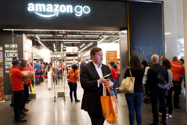 A customer carries his shopping bag as she walks out of a newly-opened Amazon Go store, Tuesday, May 7, 2019 in New York. [Photo: AP/Mark Lennihan]