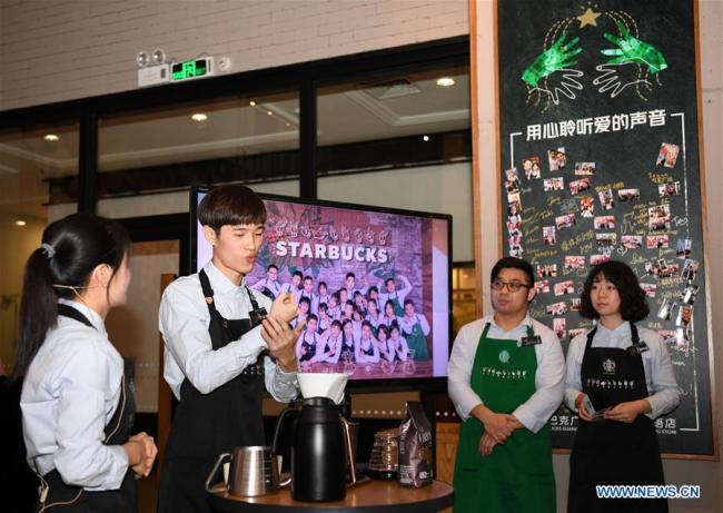 A hearing impaired staff member (2nd L) narrates culture of coffee with sign language as his colleagues look on in a Starbucks coffee store in Guangzhou, south of China's Guangdong Province, May 19, 2019. [Photo: Xinhua]