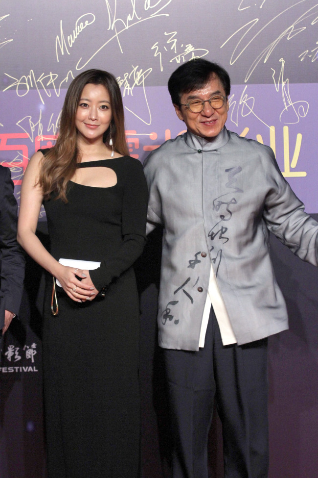 South Korean actress Kim Hee-sun, left, and Hong Kong Kung Fu star Jackie Chan arrive on the red carpet for the Jackie Chan Action Movie Week gala night in Shanghai, China on June 16, 2016. [Photo: IC]