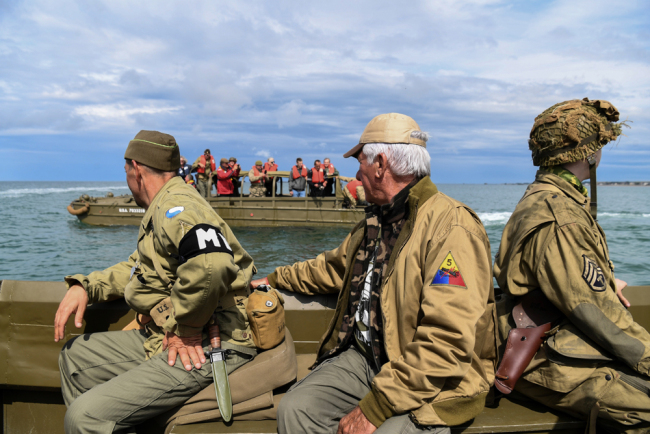 Men dressed as GIs sit on a DUKW (colloquially known as Duck), a six-wheel-drive amphibious modification of the 2 1/2-ton CCKW trucks used by the US military during World War II, on June 4, 2019 off the shores of Arromanches-les-Bains, as part of events for the 75th anniversary of D-Day landings. [Photo: AFP/Alain Jocard]