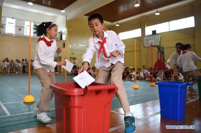 Pupils take part in a garbage sorting game(游戏 yóuxì) at Zhaoxia Primary School in Hefei, capital of east China's Anhui Province, June 4, 2019. [Photo: Xinhua]