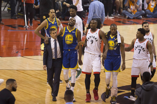 Golden State Warriors forward Kevin Durant (35) walks off the court after sustaining an injury as he is consoled by Toronto Raptors center Serge Ibaka (9) as Warriors forward Andre Iguodala (9) and guard Kyle Lowry (7) look on during first-half basketball action in Game 5 of the NBA Finals in Toronto, Monday, June 10, 2019. [Photo: Chris Young/The Canadian Press via IC]