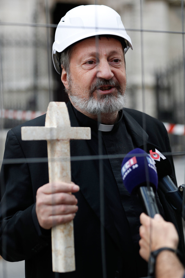 A clergyman wearing a hard hat, gives an interview prior to entering the Notre-Dame de Paris cathedral, to take part in a mass, the first since the fire that destroyed the roof on April 15, in Paris on June 15, 2019. [Photo: VCG]