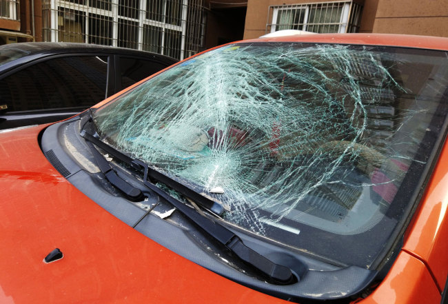 The front window of a sedan is smashed by a falling window from the 27th floor of the nearby building in Zhengzhou, Henan province, on November 21, 2018. A sanitation worker was also injured in the incident. [Photo: IC]