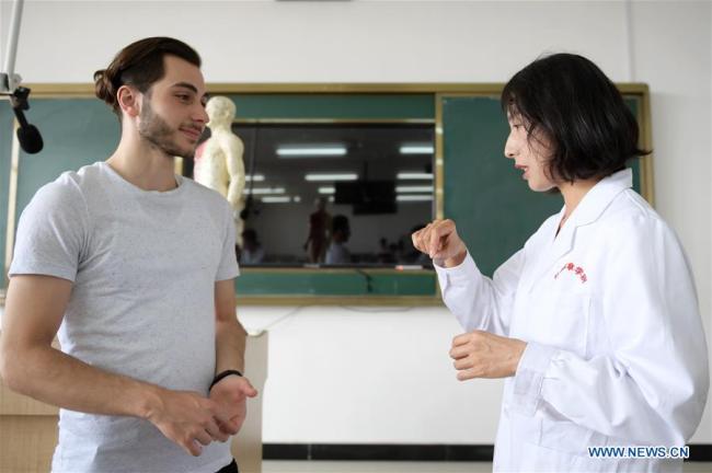 Aushev Djamaleil (L) talks with his teacher Li Na after class in Shaanxi University of Chinese Medicine in northwest China's Shaanxi Province. [Photo: Xinhua] 