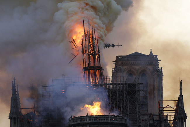 This file photo taken on April 15, 2019 shows the steeple and spire collapses as smoke and flames engulf the Notre-Dame Cathedral in Paris. A badly stubbed-out cigarette or an electrical fault could have started the devastating fire that ripped through Notre-Dame cathedral in April, Paris prosecutors said on June 26, 2019, ruling out any criminal intent. [File photo: AFP/Geoffroy Van Der Hasselt]