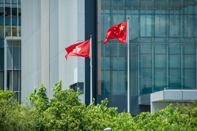 The national flag and the regional flag fly outside of the government building of Hong Kong Special Administrative Region, June 17, 2015. [Photo: VCG]
