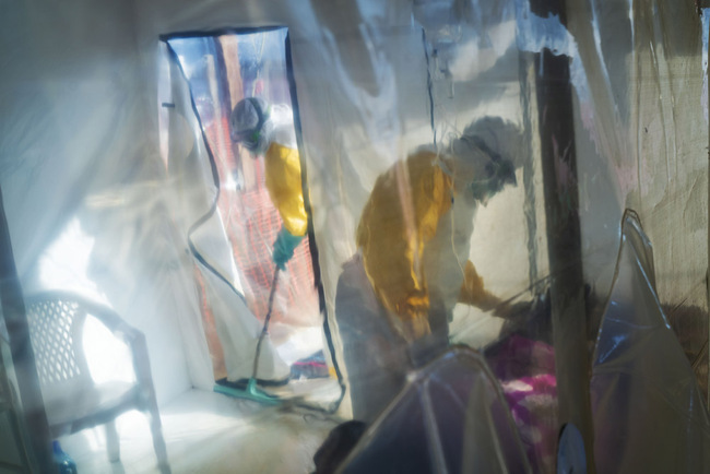 In this photograph taken Saturday 13 July 2019, health workers wearing protective suits tend to to an Ebola victim kept in an isolation cube in Beni, Congo DRC. The Congolese health ministry is confirming the country's first Ebola case in the provincial capital of 2 million, Goma, some 360 kms ( 225 miles) south of Beni. More than 1,600 people in eastern Congo have died as the virus has spread in areas too dangerous for health teams to access. [Photo: AP/Jerome Delay]