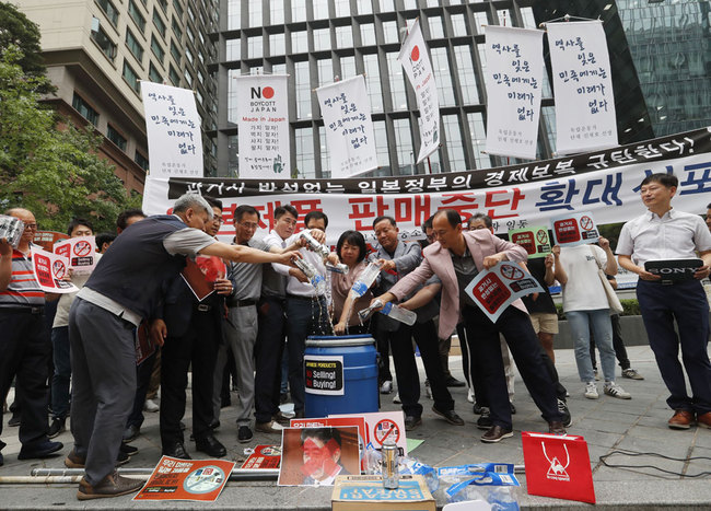 South Korean small and medium-sized business owners pour beers and drinking waters from Japanese brands into a trash can during a rally calling for a boycott of Japanese products in front of the Japanese embassy in Seoul, South Korea, Monday, July 15, 2019. [Photo: IC]