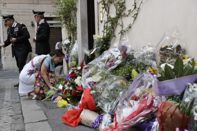 A woman leaves flowers in front of the Carabinieri station where Mario Cerciello Rega was based, in Rome, Saturday, July 27, 2019. In a statement Saturday, Carabinieri officers investigating the death Friday of officer Cerciello Rega, 35, said two American turists, both 19, have been detained for alleged murder and attempted extortion. [Photo: AP/Andrew Medichini]