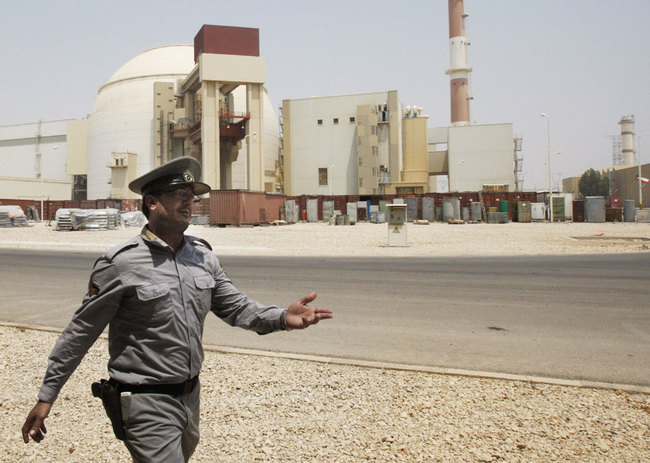 In this Saturday, August 21, 2010 file photo, an Iranian security man directs media at the Bushehr nuclear power plant, with the reactor building seen in the background, just outside the southern city of Bushehr, Iran. [File photo: IC]