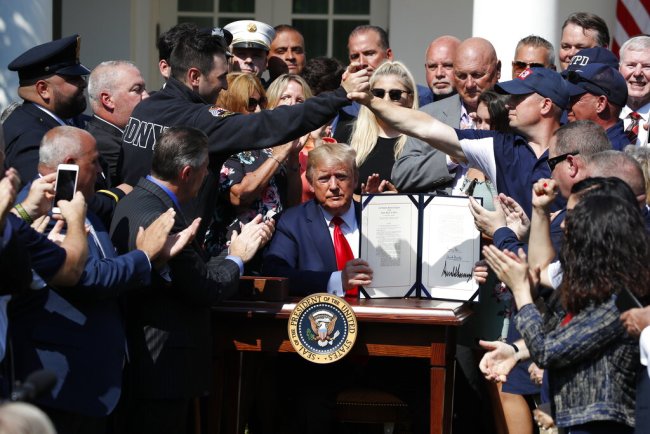 President Donald Trump holds up the signed H.R. 1327 bill, an act ensuring that a victims' compensation fund related to the Sept. 11 attacks never runs out of money, in the Rose Garden of the White House, Monday, July 29, 2019, in Washington. [Photo: AP]