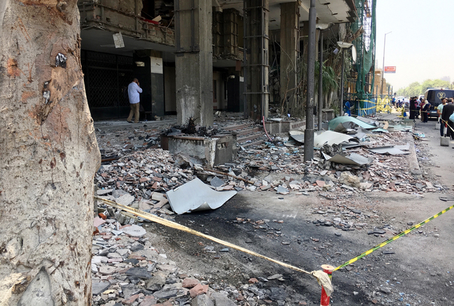 People walk in front of the damaged facade of the National Cancer Institute after an overnight fire from a blast, Cairo, Egypt, August 5, 2019. [Photo: IC]