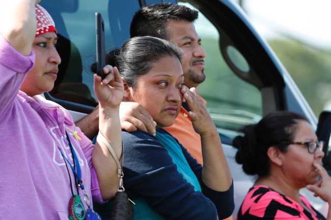 Friends, coworkers and family watch as U.S. immigration officials raid the Koch Foods Inc., plant in Morton, Miss., Wednesday, Aug. 7, 2019. [Photo: IC/ AP Photo/Rogelio V. Solis]