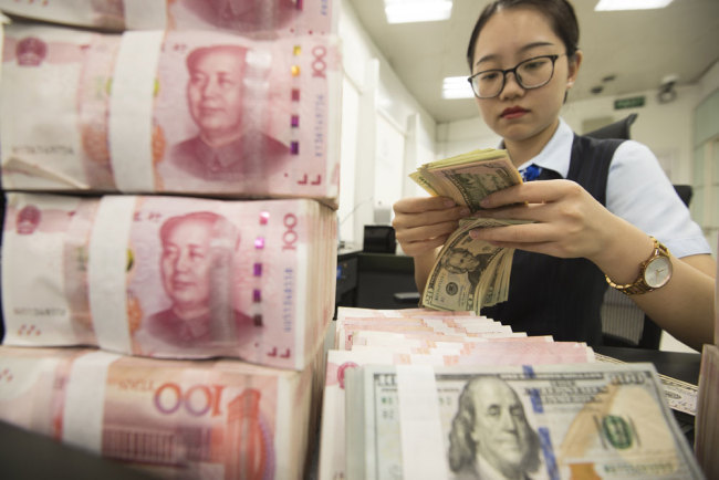 A bank clerk counts banknotes of China's yuan and U.S. dollars in a bank in Jiangsu Province on Tuesday, August 6, 2019. [File photo: VCG]