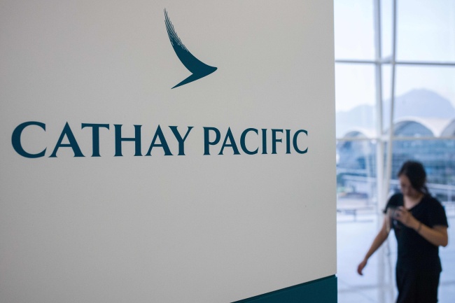 In this photo taken on August 7, 2018, a woman walks past Cathay Pacific Airways signage at Hong Kong's international airport. [File photo: AFP via VCG/Anthony Wallace]