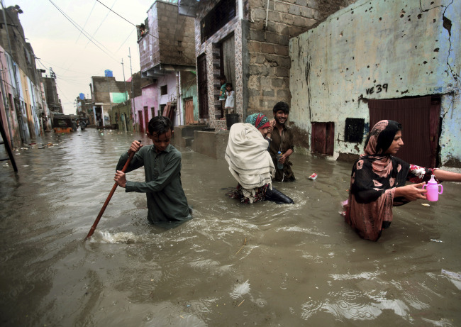 A family wades through a flooded street caused by heavy monsoon rains, in Karachi, Pakistan, Sunday, Aug. 11, 2019. [Photo: AP via IC/Fareed Khan]