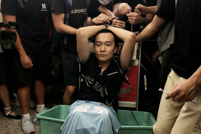 Fu Guohao, a journalist from Global Times, being tied up by Hong Kong demonstrators at Hong Kong airport. [Photo: VCG]