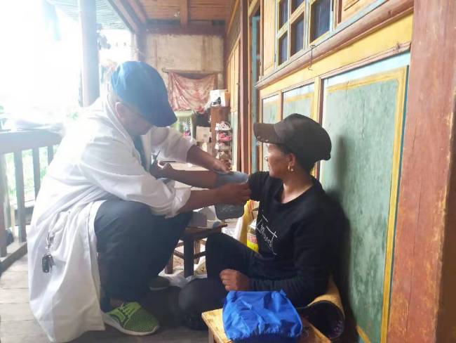 Longchen Tsodo was teaching Tashi Lhamo that had won the battle with breast cancer how to use blood-pressure meter during a recent visit. [Photo: from China Plus]  