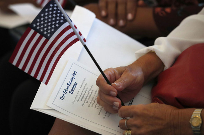 In this Aug. 16, 2019, file photo a citizen candidate holds an American flag and the words to The Star-Spangled Banner before the start of a naturalization ceremony at the U.S. Citizenship and Immigration Services Miami field office in Miami. [Photo: AP/Wilfredo Lee]