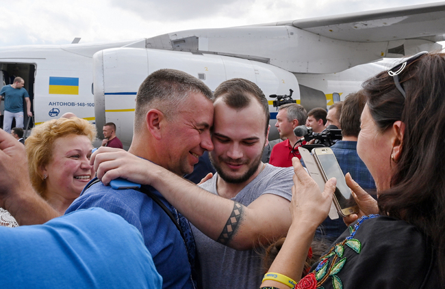 A former prisoner hugs relatives after he disembarked from a plane on September 7, 2019 at Boryspil international airport in Kiev after a long-awaited exchange of prisoners between Moscow and Kiev, a day after Russian President said for the first time the "large-scale" prisoner exchange with Ukraine was being finalized. [Photo: AFP/Sergei Supinsky]