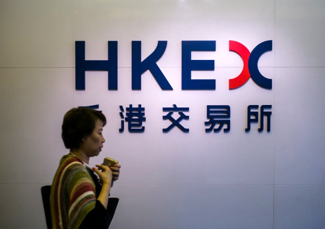 A woman walks past signage for the Hong Kong Exchanges and Clearing Limited (HKEX) outside the stock exchange in Hong Kong on November 17, 2016. [File Photo: AFP]