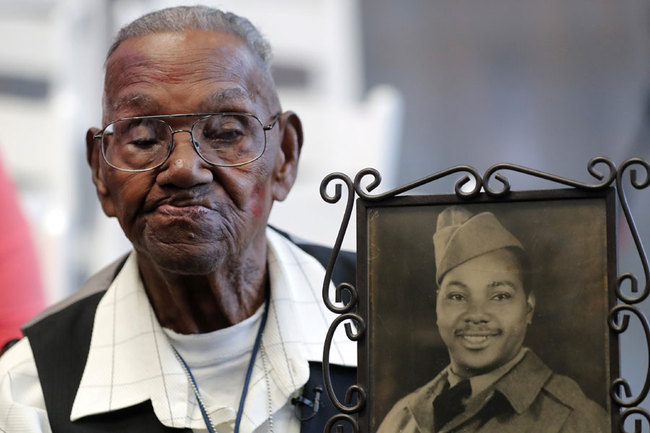 World War II veteran Lawrence Brooks holds a photo of him taken in 1943, as he celebrates his 110th birthday at the National World War II Museum in New Orleans, Thursday, Sept. 12, 2019. Brooks was born Sept. 12, 1909, and served in the predominantly African-American 91st Engineer Battalion, which was stationed in New Guinea and then the Philippines during World War II. He was a servant to three white officers in his battalion. [Photo: AP/Gerald Herbert]