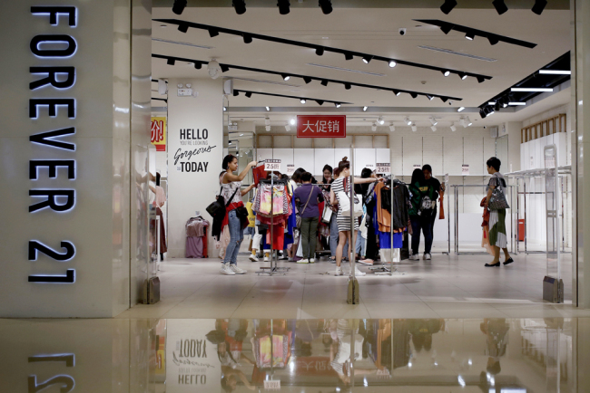 Women select clothing at an American fast fashion retailer Forever 21 which is offering clearance discounts at a shopping mall after it pulled out from China's market, on May 7, 2019, in Beijing. [Photo: AP/Andy Wong]
