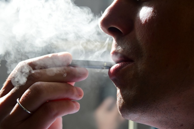 File Photo: In this file photo taken on October 02, 2018 a man is seen exhaling smoke from an electronic cigarette in Washington, DC. [Photo: AFP/Eva Hambach]