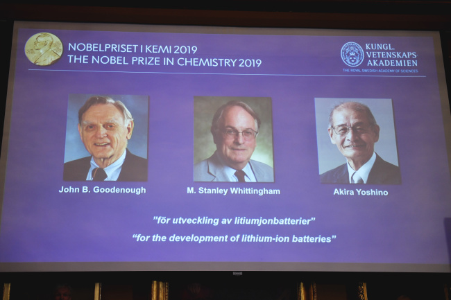 A screen displays the laureates of the 2019 Nobel Prize in Chemistry, from left, John B. Goodenough, M. Stanley Whittingham, and Akira Yoshino "for the development of lithium-ion batteries", during a news conference at the Royal Swedish Academy of Sciences in Stockholm, Sweden, Wednesday Oct. 9, 2019. [Photo: TT via AP/Naina Helen Jama]
