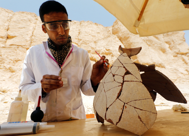 An Egyptian archaeologist works on objects discovered through an archaeological mission in the Monkey Valley near the Valley of the Kings in Luxor, Egypt, October 10, 2019. [Photo: Reuters via VCG]