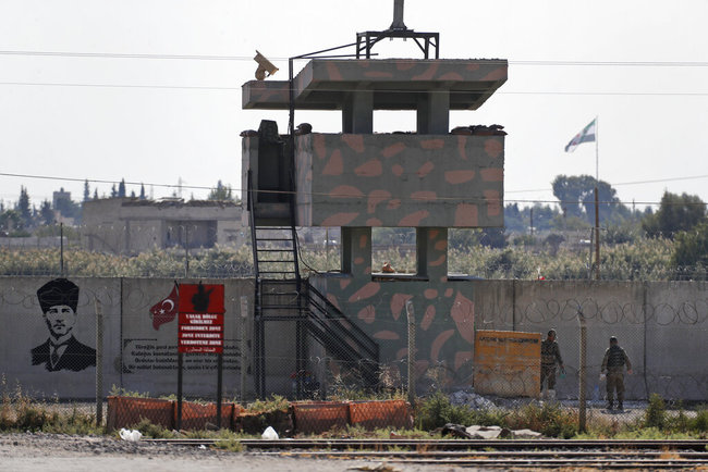 Turkish soldiers stand at an outpost in the town of Akcakale, Sanliurfa province, southeastern Turkey, Monday, Oct. 21, 2019, overlooking the town of Tal Abyad, Syria, with Syria's opposition flag flying from a pole in background right. [Photo: AP]