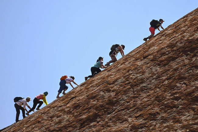 Tourists climb the sandstone monolith called Uluru that dominates Australia's arid center at Uluru-Kata Tjuta National Park, Friday, Oct. 25, 2019, the last day climbing is allowed. [Photo: AP]