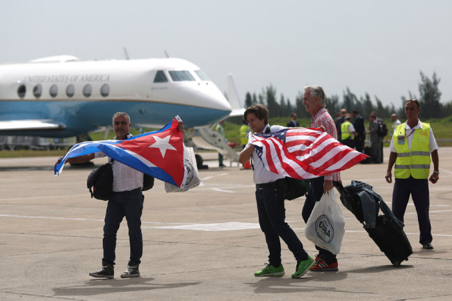 Passengers of a JetBlue aeroplane, the first commercial scheduled flight between the United States and Cuba in more than 50 years, carry U.S. and Cuban national flags after landing at the Abel Santamaria International Airport in Santa Clara, Cuba, August 31, 2016. [File Photo: IC]