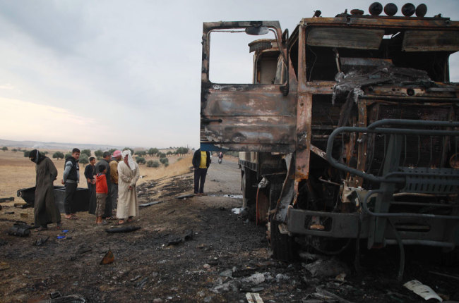 A picture taken on October 28, 2019, shows Syrian locals checking a destroyed truck at the spot where Abu Hassan al-Muhajir, the Islamic State (IS) group's spokesman was reportedly killed in a raid in the northern Syrian village of Ayn al-Bayda near Jarablus. [Photo: AFP/Aaref Watad]