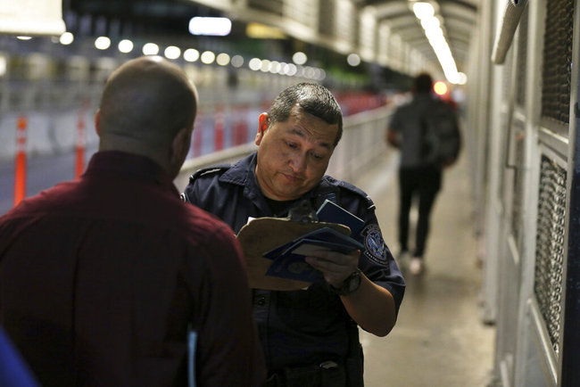 In this Sept. 17, 2019 file photo A U.S. Customs and Border Protection officer checks the documents of migrants who are on their way to apply for asylum in the United States, on International Bridge 1 as they depart Nuevo Laredo, Mexico. [File photo: AP]