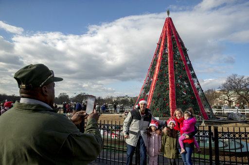 A National Park Service employee takes a photograph for George Atallah, his wife Holly and their three children Samia, 8, Elise, 6, and Noor, 3, for their annual Christmas Eve tradition at the National Christmas Tree on the Ellipse near the White House, Monday, Dec. 24, 2018, in Washington. [Photo: AP]