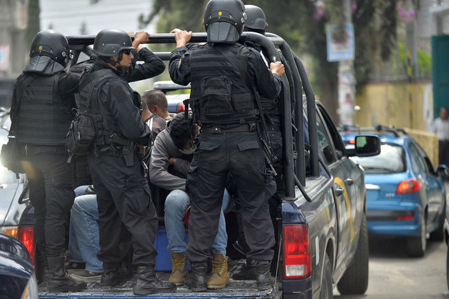 Police Special Operations Group (GOPES) officers carry arrested suspects in a van after a shoot-out in which eight allegedly drug traffickers were shot dead by Mexican Navy in Tlahuac, Mexico City, on July 20, 2017. [Photo: VCG]