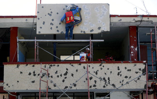 Workers repair the facade of City Hall riddled with bullet holes, in Villa Union, Mexico, Monday, Dec. 2, 2019. [Photo: AP]