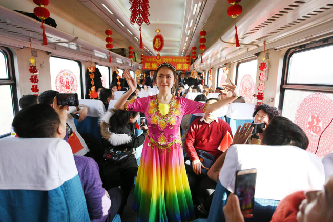 A woman from Xinjiang Uygur Autonomous Region performs Uygur dance on a train heading for Urumqi. [File Photo: VCG]