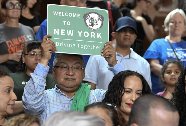 In this June 17, 2019 file photo, a protester holds a sign as members of the state Assembly speak in favor of legislation of the Green Light Bill, granting undocumented immigrant driver's licenses during a rally at the state Capitol, in Albany, N.Y. [Photo: AP]