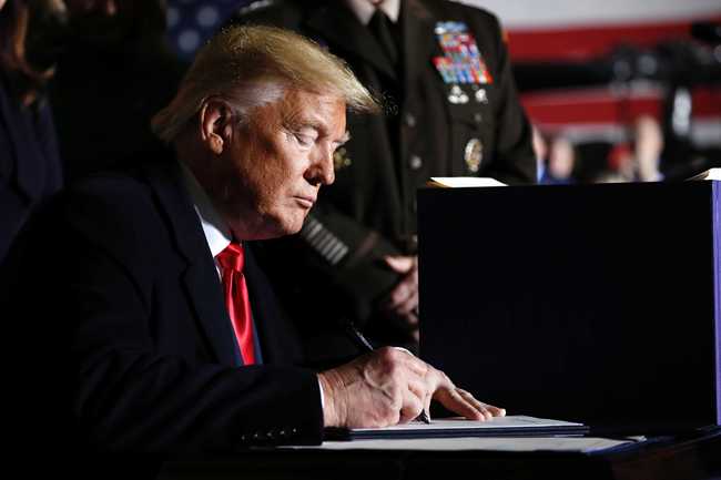 President Donald Trump signs the National Defense Authorization Act for Fiscal Year 2020 at Andrews Air Force Base, Md., Friday, Dec. 20, 2019. [Photo: AP/Andrew Harnik]